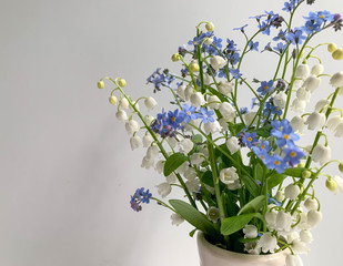 Spring bouquet of lilies of the valley and blue flowers on a white background. Spring flowers. A gift to your loved ones.