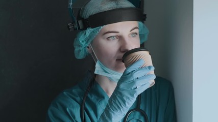 Wall Mural - tired medical worker doctor holding a paper cup of coffee after taking a large number of patients due to the epidemic of coronavirus