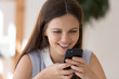 © fizkes - Close up of happy millennial girl have fun texting messaging on modern smartphone gadget, smiling young woman browse surf wireless Internet on cellphone device, new technology, Wi-Fi concept