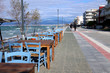 People walking on Peraia beach, Thessaloniki, Greece. View of colorful chairs and tables of a cafe.