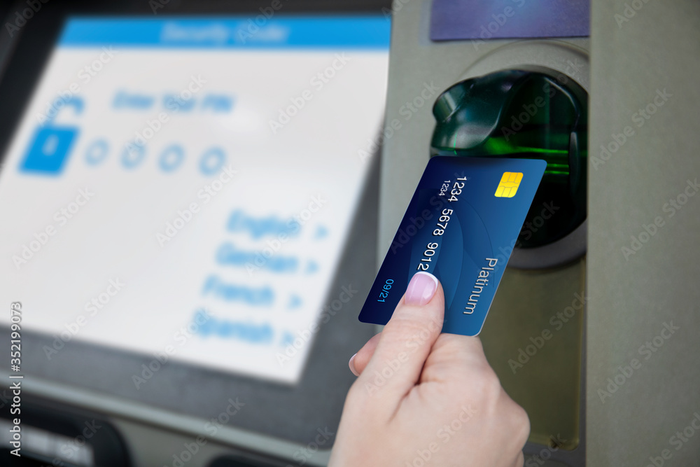 female hand holds credit card at ATM - obrazy, fototapety, plakaty 