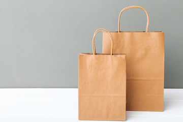  Brown craft paper bags. Empty cardboard paper package. Shopping Mockup bags on white table gray background with copy space. Shopping Food delivery service.