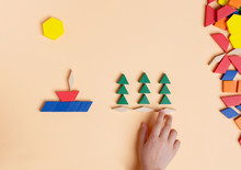 Idyllia - The Sun Is Shining, A Boat Floating On The Sea, Trees, Pines Grow. A Child Plays With Colored Blocks Constructs A Model On A Light Background.