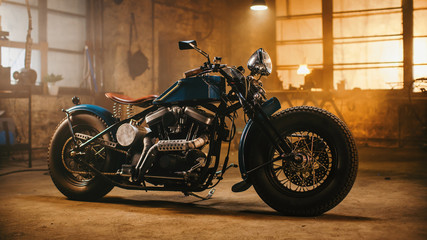 Custom Bobber Motorbike Standing in an Authentic Creative Workshop. Vintage Style Motorcycle Under Warm Lamp Light in a Garage.