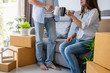 © Kittiphan - Young happy couple moving in new home, sitting and relaxing on sofa with stack of cardboard boxes