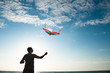 © ruslanshug - young active caucasian man with flying multicolored kite on sea and blue sunset sky background