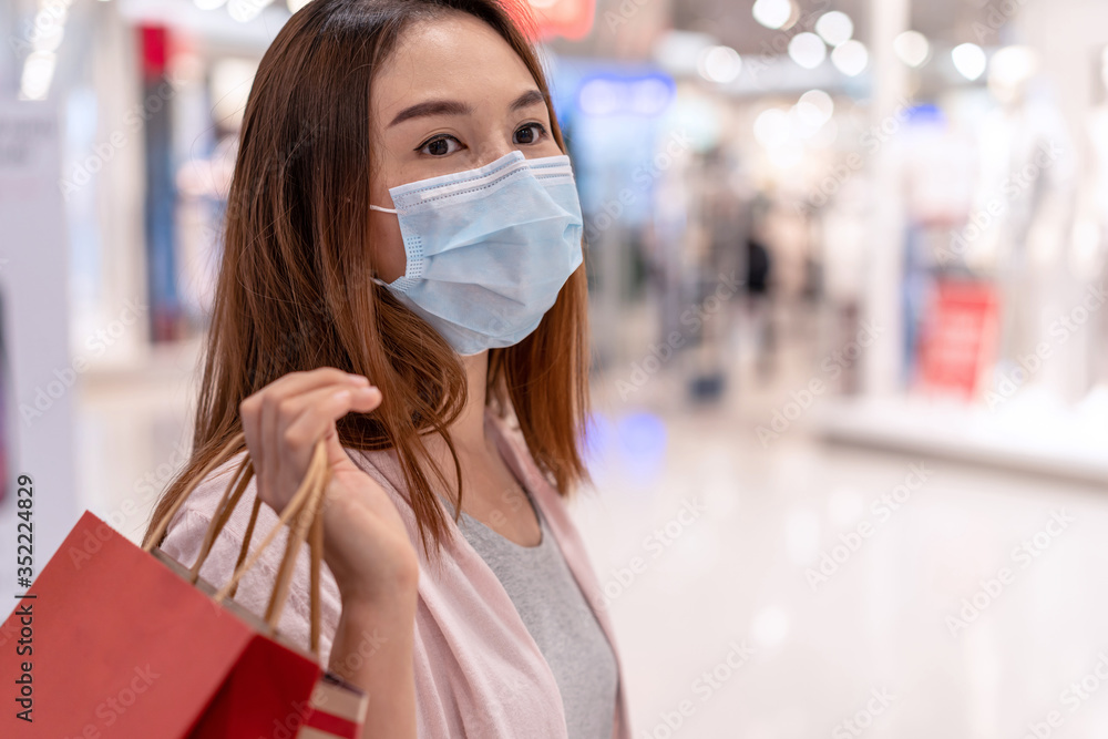 Young asian woman wearing surgical mask shopping in clothes store at the mall, New normal and lifestyle concept - obrazy, fototapety, plakaty 