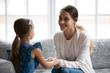 © fizkes - Smiling young Caucasian mom and little daughter sit holding hands make peace reconcile after fight, happy loving mother and small girl child talk share secrets, enjoy tender close moment at home