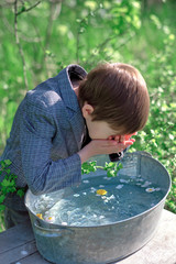 a boy washes himself with clean water from an iron basin with delicate flowers