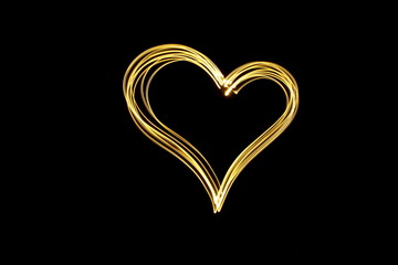 Wall Mural - Long exposure photograph of neon gold colour in an abstract heart shape outline, parallel lines pattern against a black background. Light painting photography.