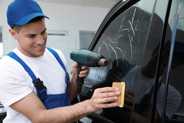 Canvas Print - Worker tinting car window with foil in workshop