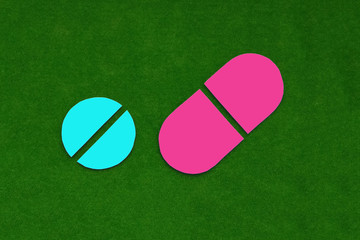 Two blue and pink tablets on a green background. medicines.