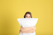 © New Africa - Young woman with pillow on yellow background
