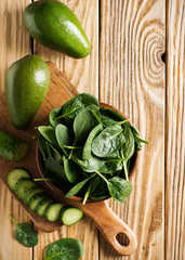 Wall Mural - Baby spinach and avocado in wooden bowl on table, green healthy ingredient