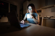© Михаил Решетников - Caucasian woman in glasses sits at a wireless computer in the kitchen. A student prepares for the exam late at night and drinks coffee so as not to fall asleep. Girl studying on a laptop in the dark.