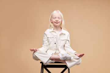 unusual alien albino child sit in yoga pose isolated in studio, keep calm and stay patient. in lotus pose