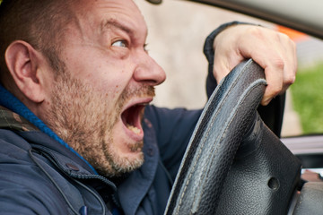 Wall Mural - A man screams at the wheel of a car. Shocked driver. A scream of fear of a traffic accident.