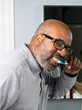 © SimoneO - African American Man brushing teeth in bathroom.  Dental health care using toothbrush and tooth paste.