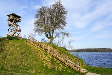  a wooden bird watching tower on top of a hill by the lake