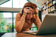 © bnenin - Close-up portrait of a stressed woman looking at received letter, holding head in hands.