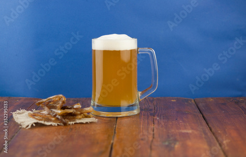 Dried fish in the shape of a straw with beer glass on wooden table. Salted fish delicacies on a table. Close-up.