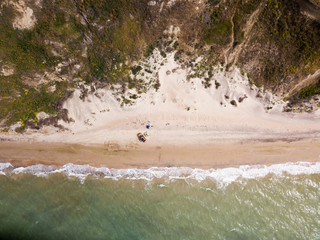 Top down view of waves breaking in the sand, flying over tropical sandy beach and waves