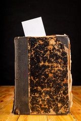 Bookmark in an old book on a wooden table. Marked places of important places and quotes. Light background.