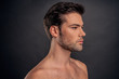 © Roman - Handsome young bearded man isolated. Portrait of shirtless muscular man is standing on grey background. Men care concept.