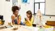 © Svitlana - Nurture happiness. African american woman baby sitter entertaining caucasian cute little girl. Kid drinking tea while having lunch with her nanny. Leisure activities, babysitting concept