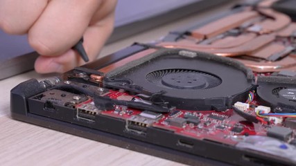 Wall Mural - Man carefully cleans dirt from laptop cooling system with silicone dust blower cleaner tool and soft brush, close up. Advertisement of repair service for electronics and devices.