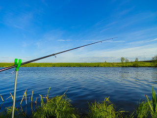 Wall Mural - Fishing on a pond with fishing rods. Beautiful pond and fishing rods on the background of the pond.