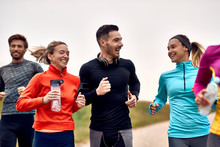 Group Of Athletic Friends Talking While Jogging In Nature.