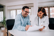 © bnenin - Positive patient and doctor talking and looking at document.