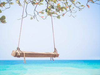 Empty swing on blurred image of blue sea background.