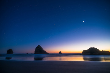 Night landscape of pacific ocean beach in USA, cliffs, and night stars. Beautiful sunset