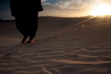Low Section Of Person Walking On Desert Land During Sunset