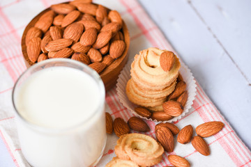 Canvas Print - almond milk glass and cookie for breakfast health food - almonds nuts on wooden bowl background