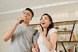 © DragonImages - Cheerful talented young couple singing songs in microphones together at home