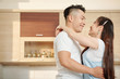 © DragonImages - Handsome young Vietnamese man looking at his beautiful wife when they are dancing in kitchen