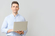 © Pixel-Shot - Handsome businessman with laptop on light background