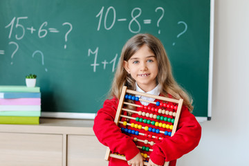 Little girl near school blackboard in classroom