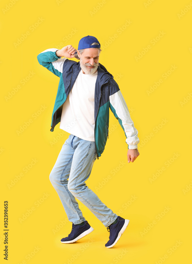 Cool senior man dancing against color background