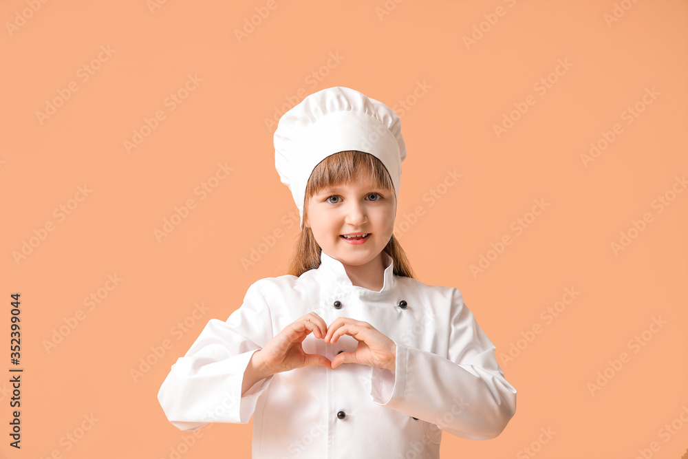 Cute little chef making heart with her hands on color background