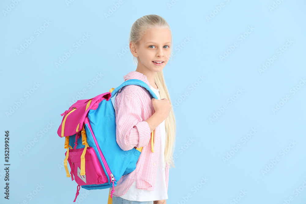 Cute little schoolgirl on color background