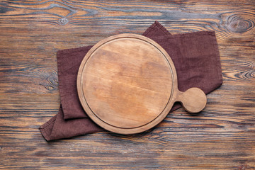 Cutting board with napkin on wooden background