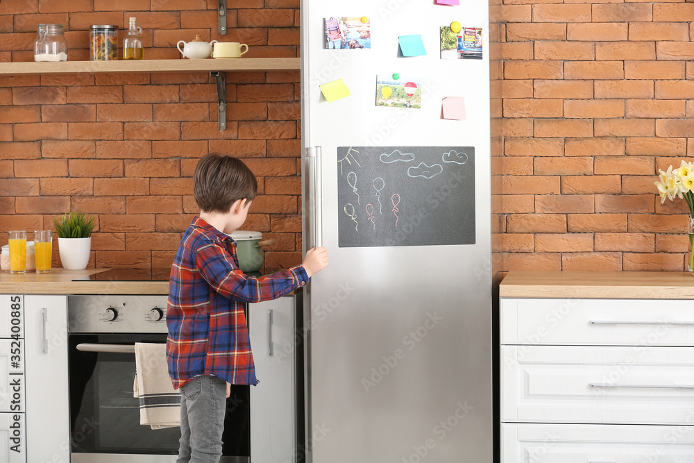 Little boy opening refrigerator in kitchen