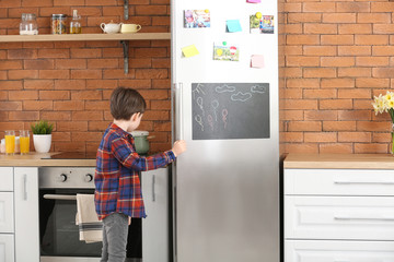 Canvas Print - Little boy opening refrigerator in kitchen