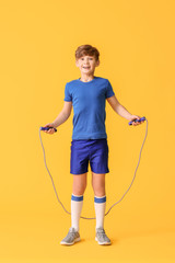 Wall Mural - Sporty little boy with jumping rope on color background