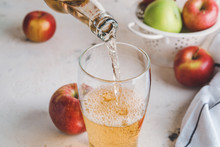 Pouring of apple cider into glass on table
