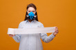 © denisval - funny woman with with toilet paper in hand in protective equipment in medical mask on yellow background, coronavirus pandemic, deficit, look at the camera